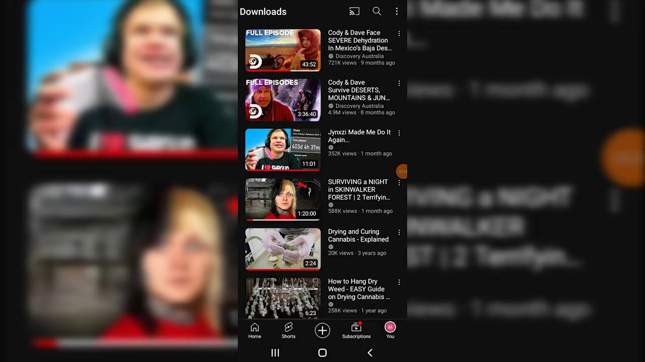 A close-up view of the YouTube app interface, highlighting the three-dotted menu or download button below a video player.
